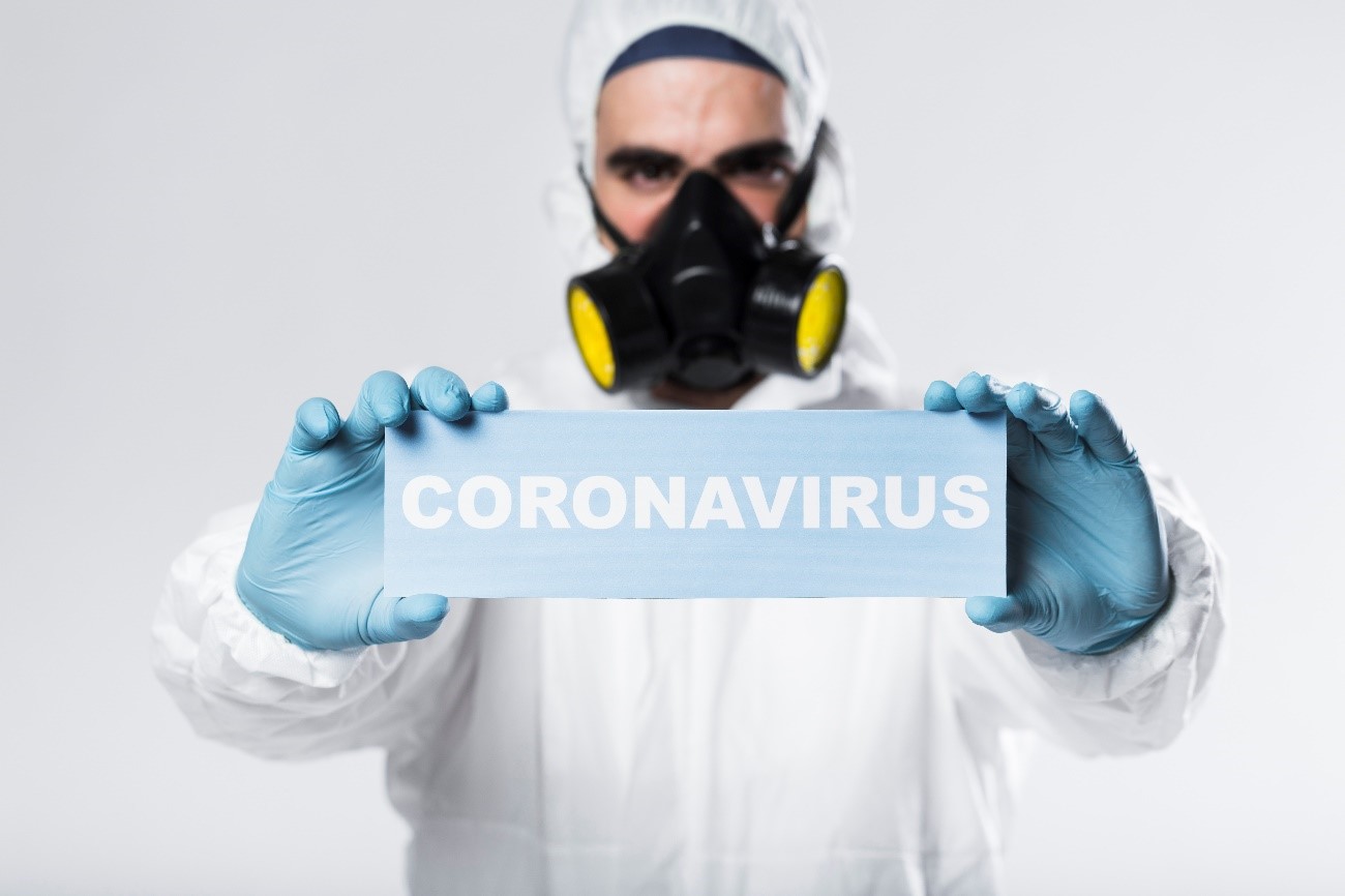 Médico com EPI's segurando placa escrito coronavírus.