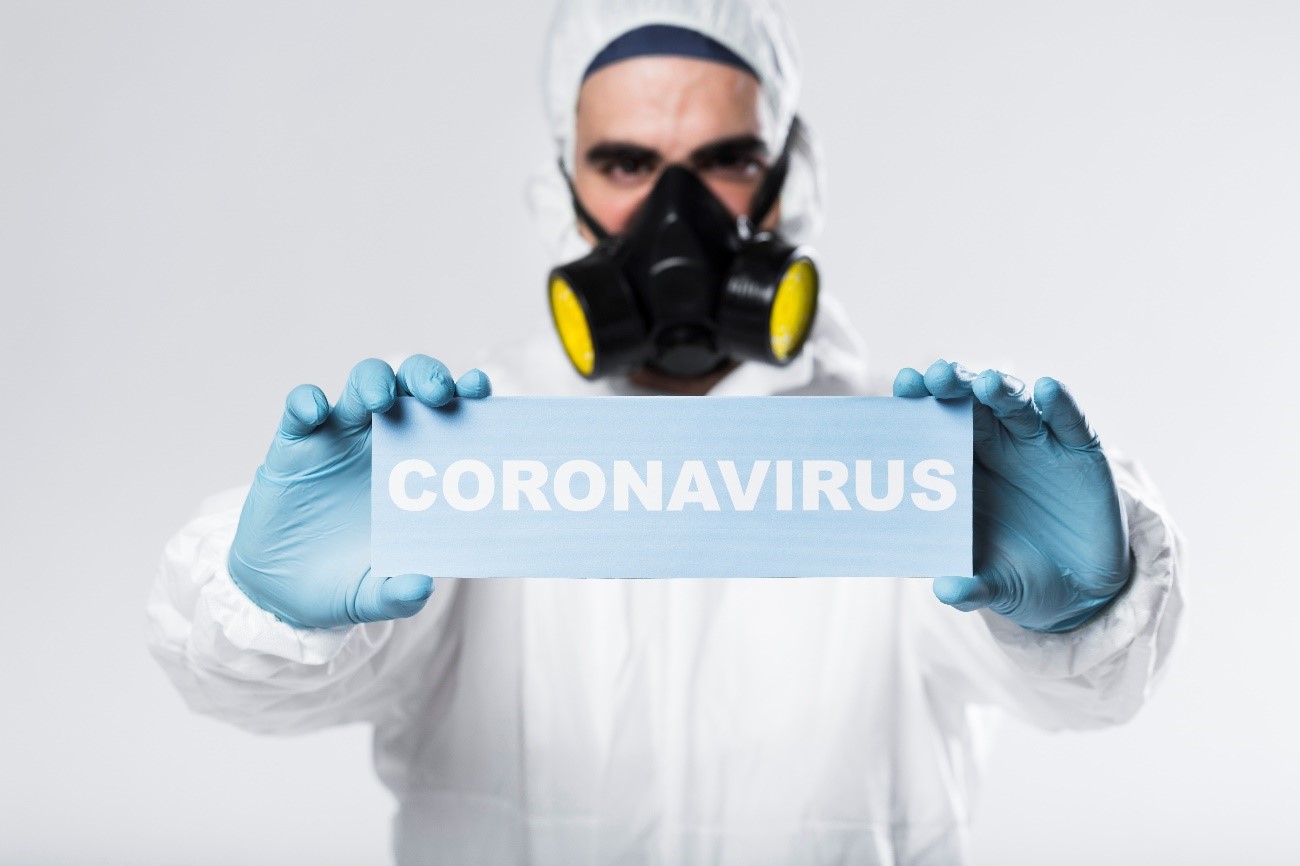 Doctor with PPI's holding plaque written coronavirus.